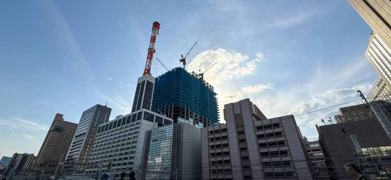 青空の下で建設が進む都市の高層ビルとクレーンの景観