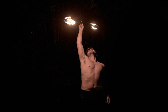 Young man practicing fire twirling performance at night