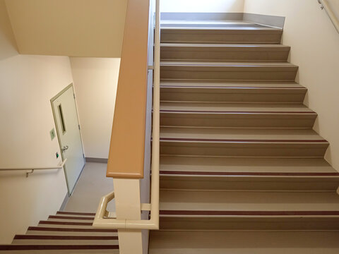 The stairwell shows safety handrails for an emergency exit in a nursing home building in Canada. The stairs lead to an exit door.