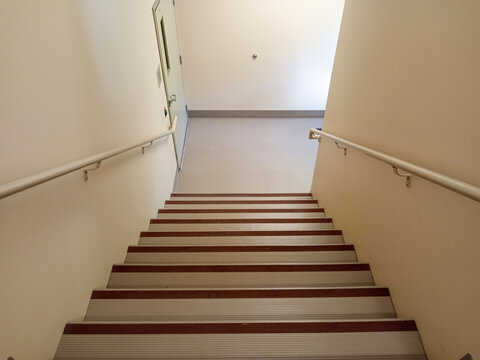 The stairwell shows safety handrails for an emergency exit in a nursing home building in Canada. The stairs lead to an exit door.