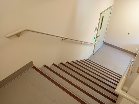The stairwell shows safety handrails for an emergency exit in a nursing home building in Canada. The stairs lead to an exit door.