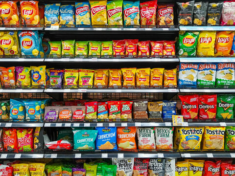 Bangkok, Thailand - February 16, 2026:  Full shelves at Villa Market in Bangkok show many brands of ultra processed junk food potato chips and unhealthy snacks.