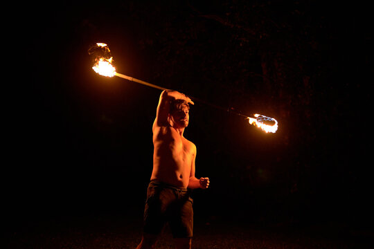 Hispanic man performing fire twirling act at night