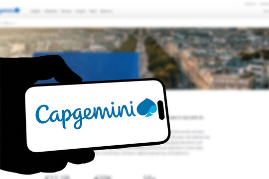 Kiel, Germany - 05-20-2026: Smartphone displaying the French IT consulting company Capgemini app in the App Store in a workspace environment with laptop and notebook