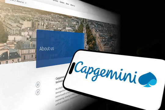 Kiel, Germany - 05-20-2026: Smartphone displaying the French IT consulting company Capgemini app in the App Store in a workspace environment with laptop and notebook