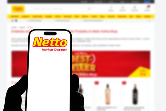 Kiel, Germany - 05-20-2026: Smartphone displaying the German discount supermarket chain Netto Marken-Discount app in the App Store in a workspace environment with laptop and notebook