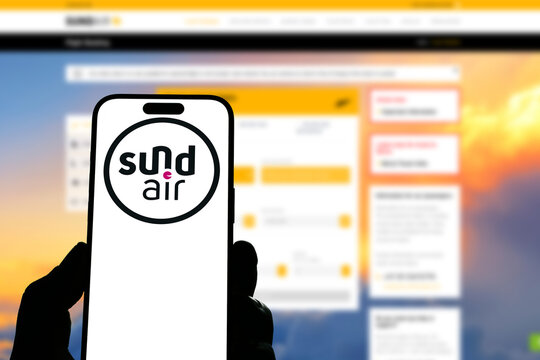 Kiel, Germany - 05-20-2026: Smartphone displaying the German airline Sundair app in the App Store in a workspace environment with laptop and notebook