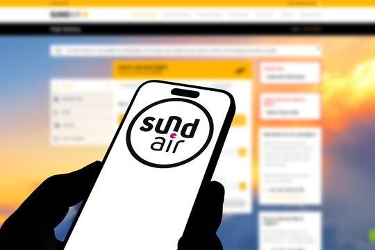 Kiel, Germany - 05-20-2026: Smartphone displaying the German airline Sundair app in the App Store in a workspace environment with laptop and notebook