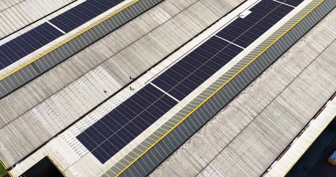 Aerial drone footage of industrial warehouse rooftops covered with solar panels in Leeds West Yorkshire UK showing renewable energy infrastructure and geometric commercial building patterns from above