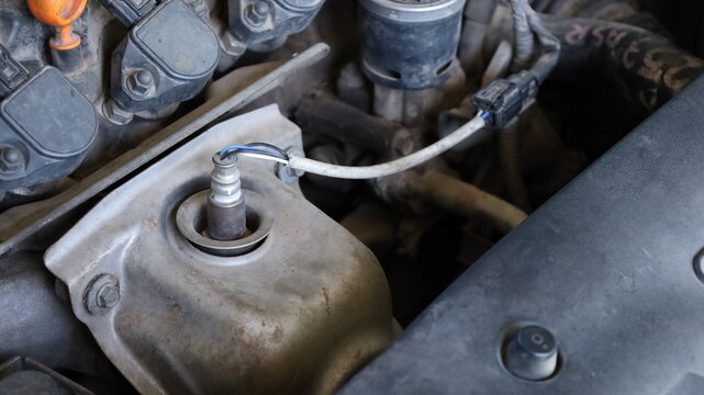 Old Oxygen Sensor. A close-up image of the old oxygen sensor on the engine compartment exhaust pipe, viewed from above with selective focus in the copying area.
