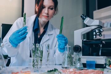 Fototapeta premium Scientists in lab coats work with plants in a modern lab, focusing on research and experimentation under bright, sterile conditions.