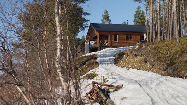 Remote off-grid wooden cabin in Swedish Lapland, surrounded by forest, snow, and mountain terrain. Ideal for travel, nature, and wilderness lifestyle content.