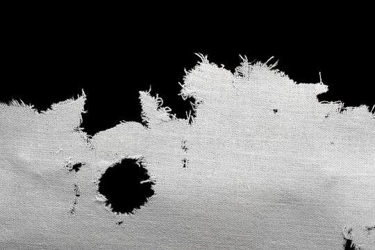 a torn old white rag, canvas with holes and fraying edges