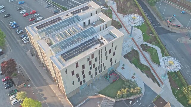 Modern civic building near Schw&auml;bisch Gm&uuml;nd Way in Barnsley, South Yorkshire, England, revealing contemporary architecture and illuminated canopy structures, overhead drone descent shot.