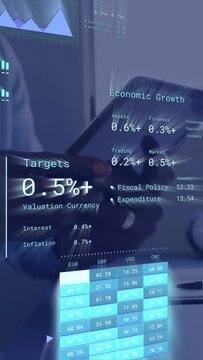 Vertical video: Finance analyst holding tablet, tapping and swiping, updating economic charts