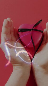 Vertical video: Hands cupping pink heart box, neon trails starting left, looping, lighting ribbon