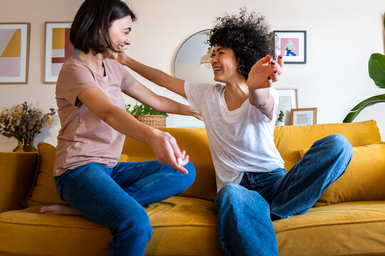 Happy friends greeting hugging on a yellow sofa