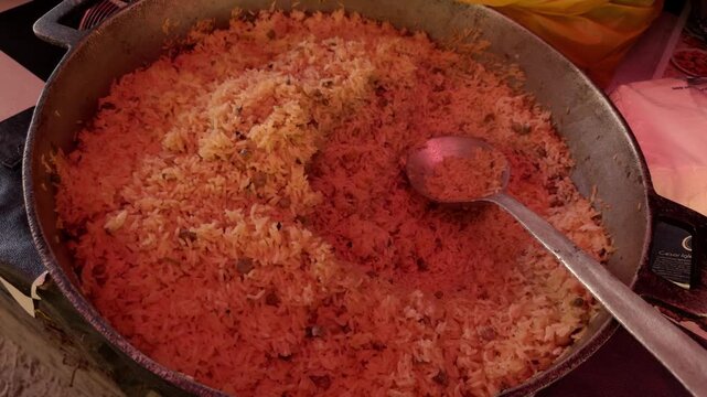 Close-up of large metal pot filled with cooked moro de guandules rice and pigeon peas with metal spoon