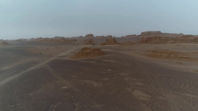 Group of yardang ridges stretch across arid desert under hazy atmosphere with wind erosion patterns visible creating vast natural rock landscape perfect for geology and wilderness stock video