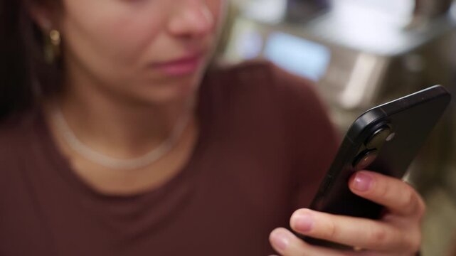Woman is lost in her smart phone while she waits for coffee.