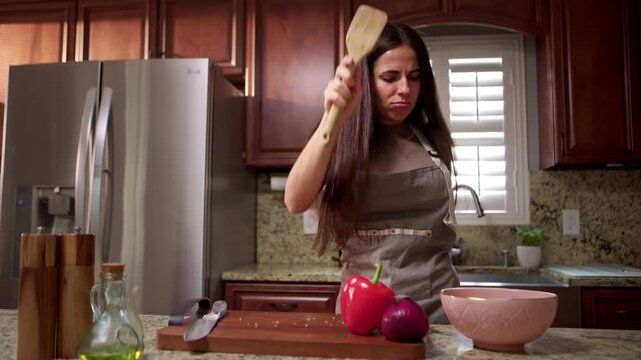 Woman makes cooking fun by singing and dancing in kitchen