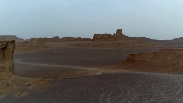 Tall yardang tower dominates the desert scene with wind-eroded base under clear sky creating striking natural rock formation vista ideal for geology and arid landscape stock video content.