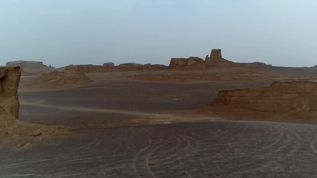 Multiple yardang formations spread across flat desert under hazy sky with wind erosion creating textured rock landscape perfect for geology and nature stock video footage.
