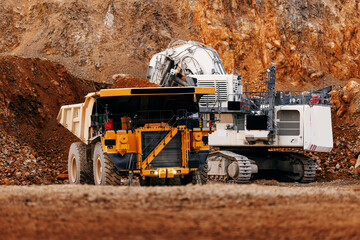Heavy mining dump truck and excavator in open gold pit mine for industrial background banner © Parilov
