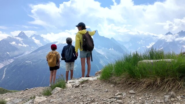 Mother pointing out the scenic mountain view to her two children while hiking on a trail, enjoying a family vacation and an active, healthy outdoor lifestyle