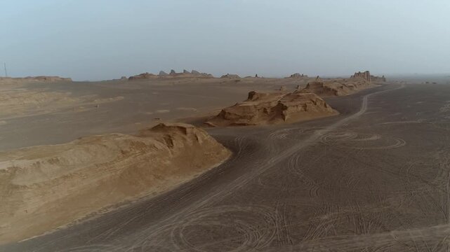 Group of yardang formations stretch across arid desert under clear sky with wind erosion creating expansive natural rock landscape ideal for geology and nature stock video content.