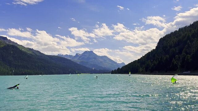 Wingsurfer and Windsurfer Surfing in a Windy Day with Mountain View in the Swiss Alps in a Sunny Summer Day in Lake Silvaplana, Silvaplana, Maloja, Grisons, Switzerland. (Time Lapse)