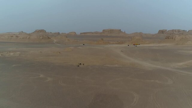 Wide yardang field spreads across desert plain under overcast sky with wind erosion creating vast natural landscape vista ideal for geology and arid stock video content.