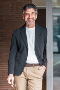 Smart mature businessman posing to camera while standing in front of the office