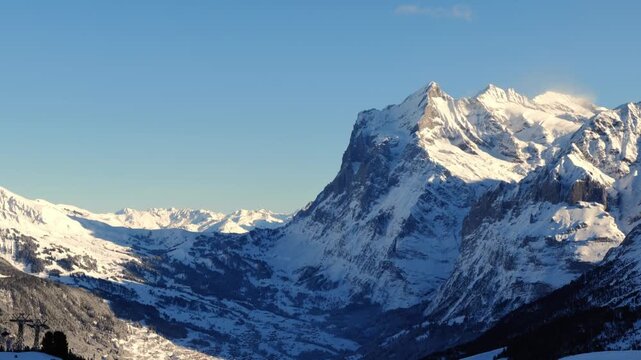 Beautiful Snowcapped Mountain Peak Wetterhorn 3692 Meters High and Valley in the Swiss Alps in a Sunny Winter Day with Blue Sky and Clouds in Grindelwald, Bernese Oberland, Bern Canton, Switzerland.