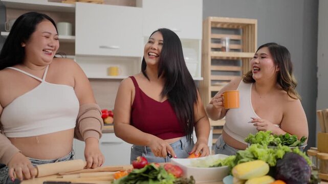 A group of three plus-size girls are having fun cooking together in the kitchen.