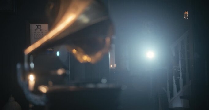 Handheld shot of woman with flashlight in haunted house quickly turning to working gramophone a couple times