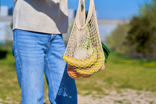 Mature woman carrying reusable mesh bag with groceries