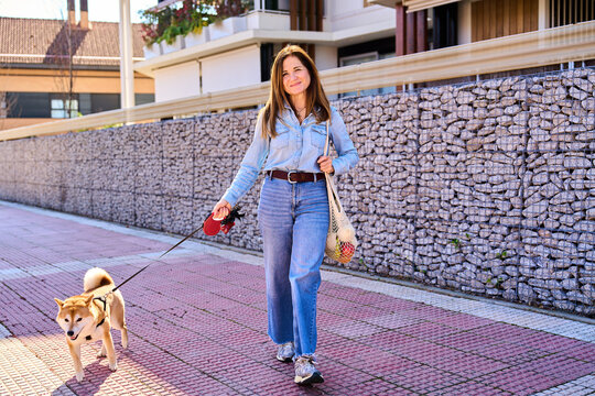 Mature woman walking dog on city street