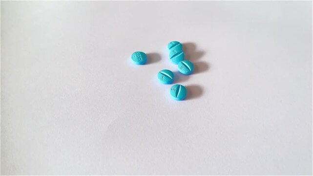 footage of hand pick blue pills on white background