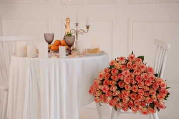 Fotobehang Eetkamer Romantic Dinner Setting with Pink Roses, Champagne, and White Candles on a Clothed Table  © Galka3250
