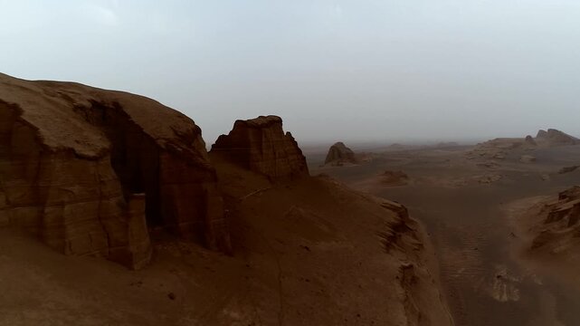 Yardang rocks with strong shadows in desert under hazy sky creating textured wind erosion landscape perfect for geology and wilderness stock video footage.