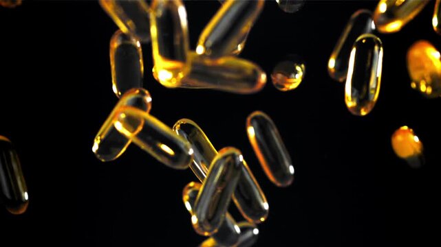 Black background glowing golden softgels floating in elegant light Filmed on a high-speed camera at 1000 fps.