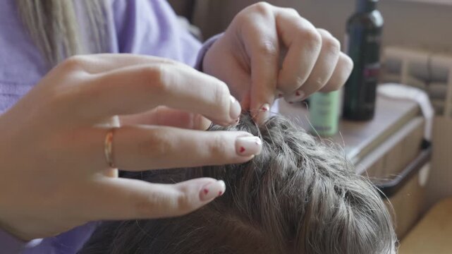 Female hands with heart nail polish carefully separate and examine strands of hair on a scalp. Concept of personal grooming, daily hygiene routines, and intimate cosmetic care.