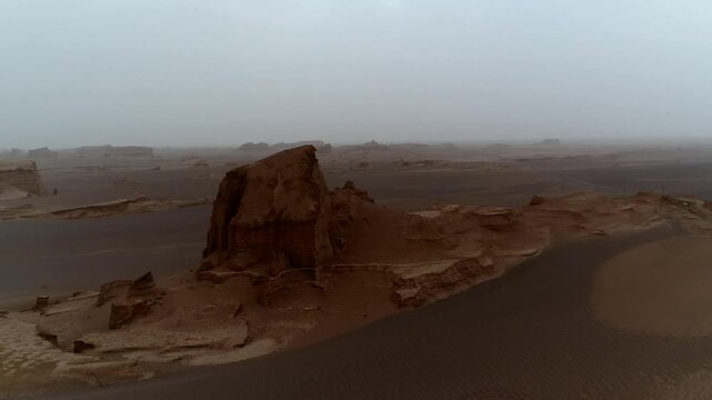 Single yardang rock formation rises in hazy desert creating isolated wind erosion scene perfect for geology and wilderness stock video footage.
