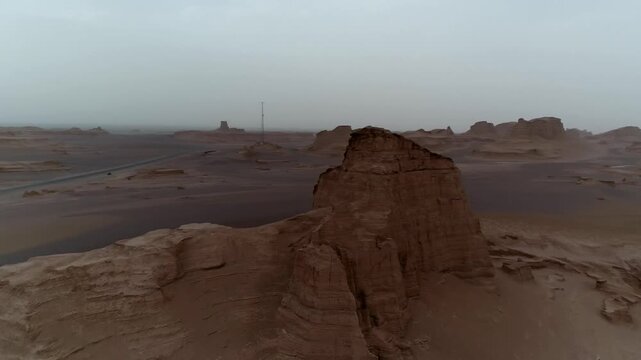 Yardang tower with eroded base stands in desert under overcast sky creating dramatic natural rock formation vista ideal for geology and landscape stock video content.