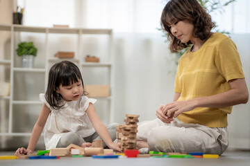 Naklejka premium Happy Asia mother play and learn toy blocks with the little girl. Funny family is happy and excited in the house. Mother and daughter having fun spending time together. Holiday, Activity, development