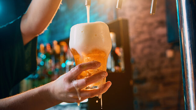 Female hand holding foamy beer glass during draft pouring. Concept of craft beer advertising, pub service, brewery promo, restaurant menu, nightlife beverage campaign, and bar hospitality.