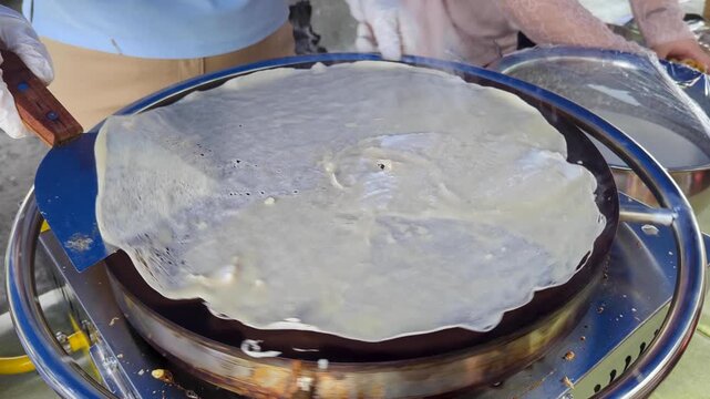 Close up making a crepe pancake on spinning hotplate at local market in capital city Suva, Fiji