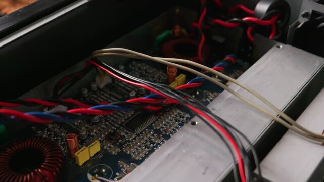 Intricate printed circuit board features a copper inductor coil, colorful twisted power cables, and microchips. Concept of electronic engineering, hardware repair, and modern technology.
