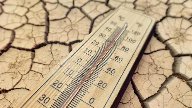 a wooden thermometer on severely cracked dry earth powerfully symbolizing extreme heat wave drought global warming ecological crisis and deadly danger for people and planet